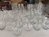 Multiple clear glass vases grouped together on a table, showing variety in shapes and sizes