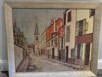 Full view of the painting showing a street with buildings and a church steeple in the background, signed and titled.
