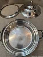 Disassembled view of Simpson Hall Miller & Co quadruple silver plate wide bowl showing lid, insert ring liner holder, and bowl with tarnish and wear.