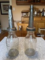Front view of both glass oil bottles with metal spouts and hinged lids