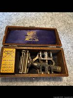 Vintage Wilkinson and Sword shaving kit in open wood case showing safety razor and yellow blade box