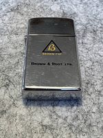 Closed view of chrome Zippo lighter with Brown & Root Ltd. logo on top surface.