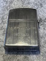 Front view of the collectible lighter showing engraved text and linear texture.