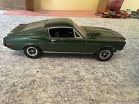 Side view of green model car showing the detailed body and metallic dark green color.