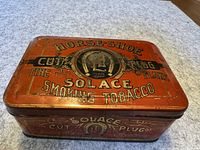 Top view of the vintage Horse-Shoe Solace Smoking Tobacco tin showing text and logo on lid.