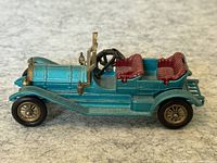 Side view of the metallic blue diecast 1909 Thomas Flyabout car with red interior seats and brass-colored trim.