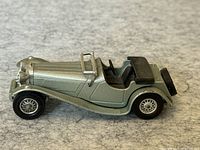 Side view of the silver diecast 1930 Jaguar model car showing detail of body, wheels, seats, and spare tire.