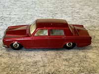 Left side profile view of the red diecast Rolls Royce toy car showing metallic paint and four-door sedan shape.