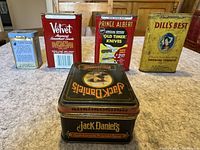 All five tobacco tins shown in one image, front view, arranged in row with Jack Daniel's tin in the front.