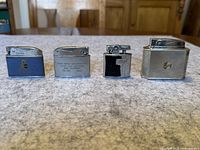 Front view of four vintage lighters arranged side by side on a table surface.