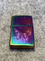 Front view of Zippo lighter showing rainbow fluorescent finish and butterfly engraving.