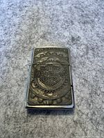 Front view of the vintage Zippo lighter showing the raised Harley Davidson Motor Cycles logo surrounded by gear design.