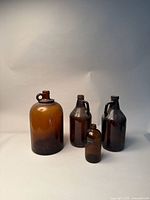 Front view of four amber glass bottles, showcasing size variation and overall condition