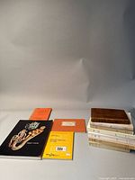 Front view of various books, including a black cover music book with a saxophone image, an orange book, a yellow book, and a brown leather book.