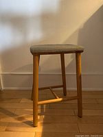 Front and side views showing natural wood frame and gray upholstered seat