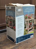 Boxed Suncast Premium Garden Center Cart packaging showing front and side with product images and features.