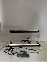 Two Jiffy Hydro grow lights with stands, power cords and mounting hardware alongside one grow bulb on flat surface.