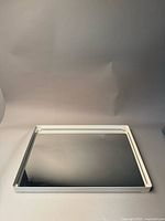 Front view of the white framed rectangular mirror on a neutral background, showing clear reflective surface and white frame.