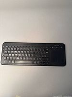 Top view of black Microsoft wireless keyboard showing French language keys and integrated touchpad