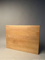Large rectangular maple wood cutting board shown standing upright against a plain background, highlighting the wood grain and size.
