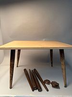 Photo showing the mid-century wood side table with attached legs and extra set of four wooden legs with two metal mounting plates placed under the table.