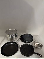 Full view of all pots and pans including stock pot, two cast iron skillets, non-stick frying pan, springform pan, and strainer.