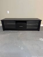 Front view of the media console showing closed glass doors and the drawer in the center.