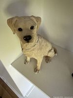 Cream colored sitting dog sculpture showing details of fur texture and face