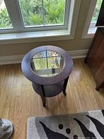 Top view showing round glass panel inset into cherry wood frame of the side table.