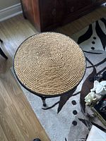 Top view of round wicker table top with tightly woven beige wicker in spiral pattern inside black metal edge.