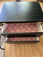 Top-down view of the black dresser top and two open drawers showing floral liners inside.