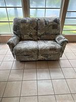 Front facing view of reclining fabric loveseat with abstract pattern showing two seats and armrests.