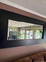Straight-on photo of the rectangular black wood frame mirror showing its size and reflection of the room.