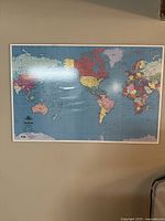 Full view of the world map mounted on the wall showing countries and continents with a color-coded scheme.