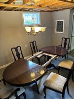 Dining table partially extended with four chairs surrounding it. Showcasing the mahogany finish and the tabletop surface.