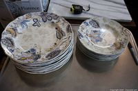 Stack of 8 large 11-inch plates and 6 smaller 9-inch plates showing the Arielle blue, gold and cream floral paisley pattern, scalloped edges visible.