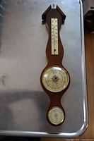 Full view of the wooden wall barometer showing integrated thermometer and hygrometer.