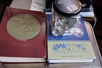Two large stamp albums (one red, one blue) and a jar with loose stamps on a wooden surface.