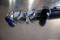 Four silver-tone costume jewelry rings displayed on a pen showing details of design and stones.