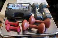 Photo of two 15 lb metal dumbbells, two red vinyl dumbbells and two brown vinyl dumbbells on a silver tray.