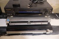 Stacked view of three electronic units including Panasonic VHS player on top, Pioneer DVD recorder in the middle, and Sony home theatre at the bottom.