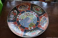 Top view of the large round dish showing the central peacock motif and surrounding decorative panels with floral and peacock designs.