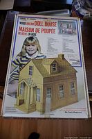 Full view of the front of the box showing the Wood Dream Doll House kit with a large child image and the assembled doll house illustration.