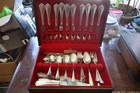 Closed box with knives arranged vertically in slots on the box lid and assorted cutlery below.