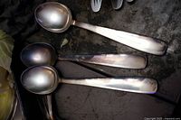 Close-up photo of six large silverware spoons marked GEG Solingen 90, showing cleaning and some patina.