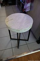 Side angle view of the mosaic tile table showing the round patterned top and metal legs.