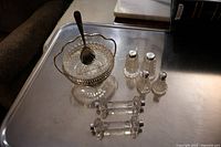 Full view of two sets of salt and pepper shakers, two cutting utensil rests, silver plate bowl with spoon on tray.