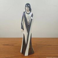 Front view of the Axia modernist Spanish porcelain figurine showing the woman in a long dress with black/dark blue geometric pattern on white background.