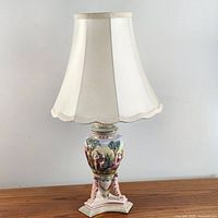 Full view of the ceramic lamp with ivory scalloped shade, showing overall shape and design