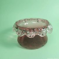 Side view of small cranberry glass bowl with clear ruffled floral trim, showing flared body and paneled sides